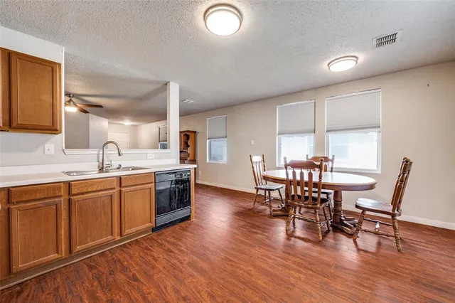 a kitchen with stainless steel appliances granite countertop wooden floor a dining table and chairs