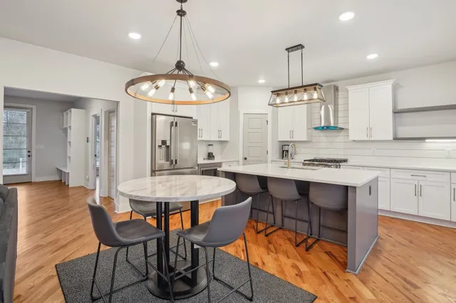 a kitchen with stainless steel appliances kitchen island granite countertop a table chairs sink and cabinets