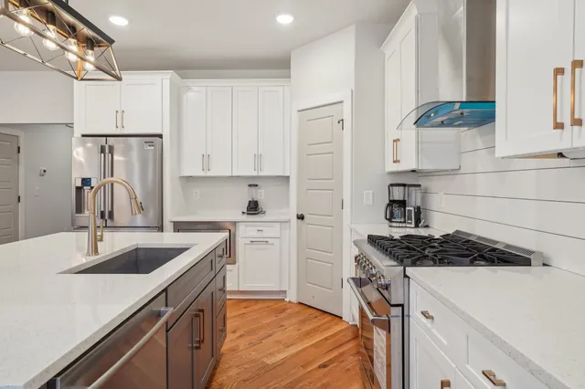 a kitchen with stainless steel appliances granite countertop a sink stove and refrigerator