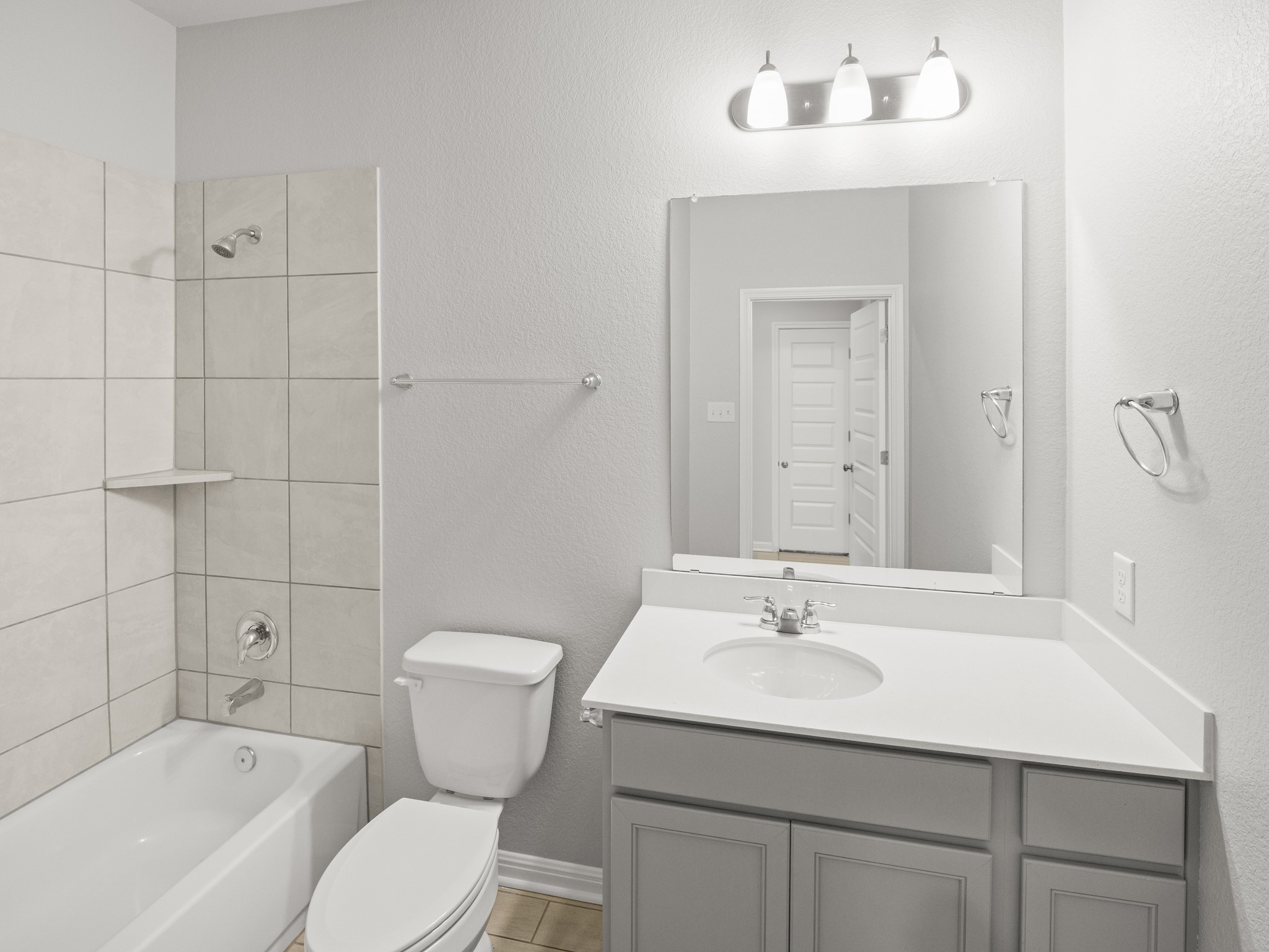 108 Drifter Lane Jarrell, TX 76537 - Photo 6 of 6 Full bathroom featuring a white porcelain tub, chrome fixtures, tiled shower surround with a built-in shelf, white vanity countertop, and a vanity light fixture