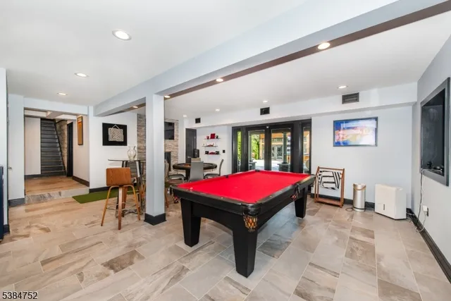 a living room with furniture pool table flat screen tv and windows