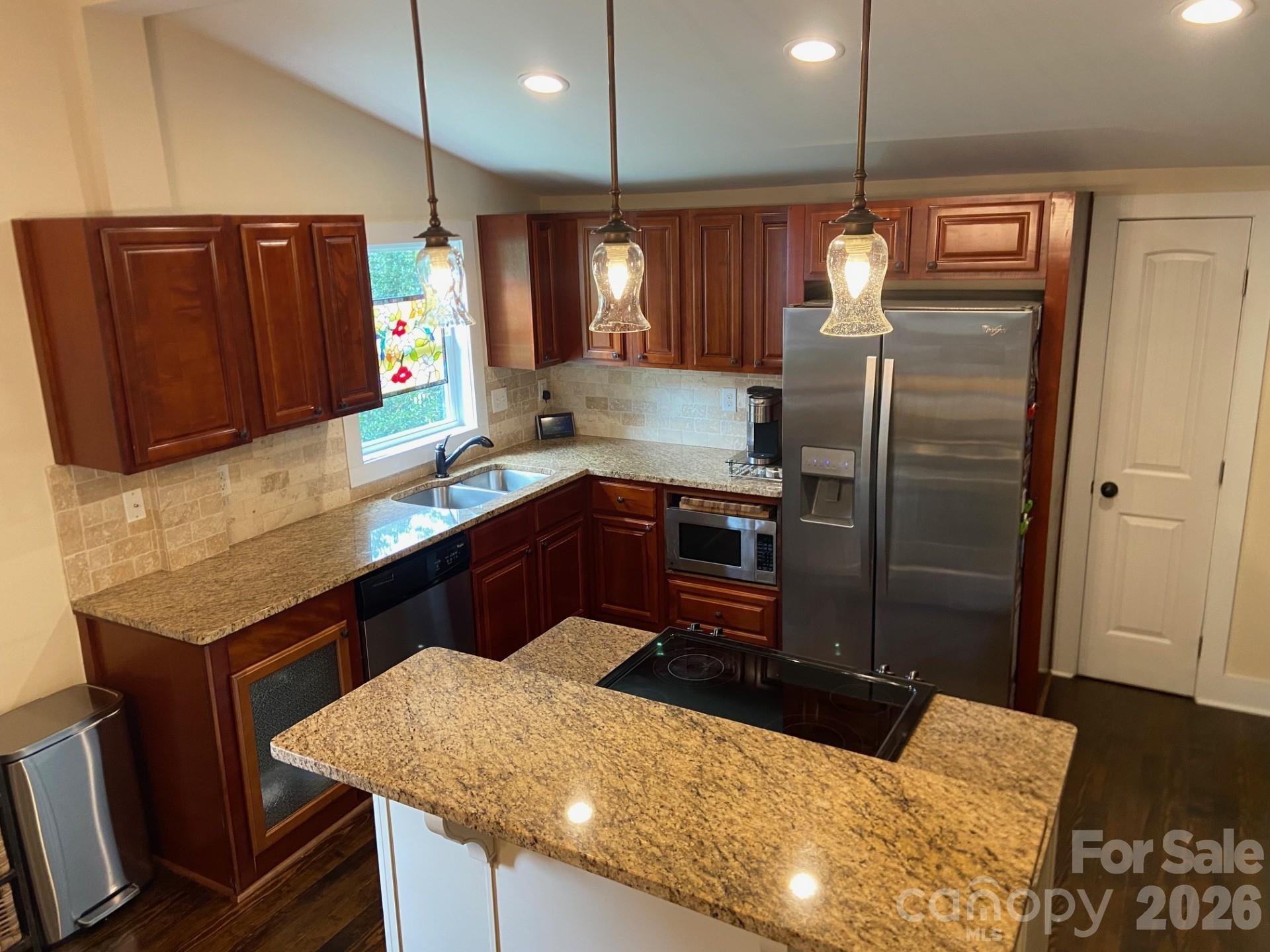 201 Main Street Matthews, NC 28105 - Photo 9 of 16 a kitchen with stainless steel appliances wooden cabinets a sink and a refrigerator