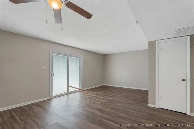 a view of an empty room with window and wooden floor