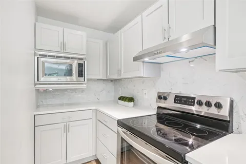 a kitchen with stainless steel appliances granite countertop a stove and white cabinets