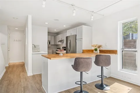 a view of kitchen with granite countertop living room and stainless steel appliances