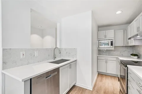 a kitchen with kitchen island a sink a stove a refrigerator and white cabinets