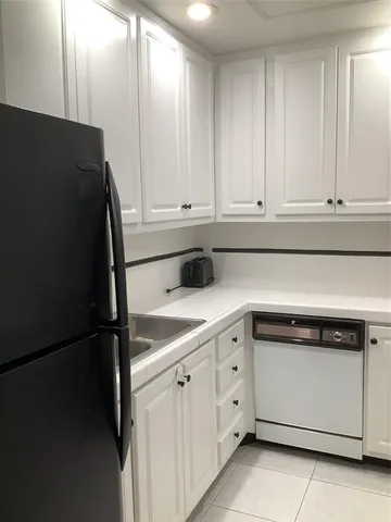 a kitchen with white cabinets and a refrigerator