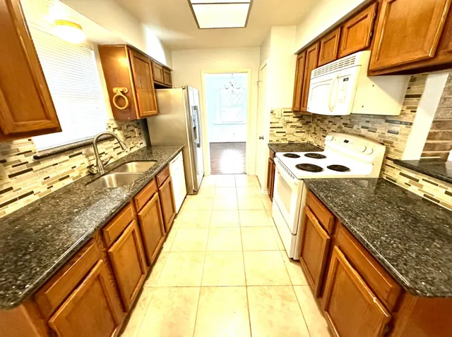 a view of a kitchen with stainless steel appliances granite countertop a sink and cabinets