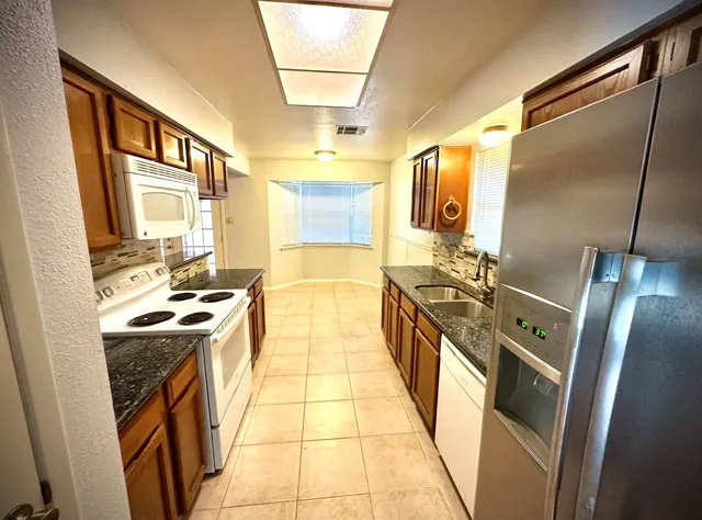 a kitchen with stainless steel appliances granite countertop a stove a sink and a refrigerator