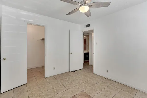 an empty room with closet and a chandelier fan
