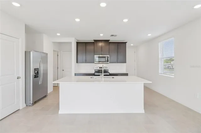 a large kitchen with stainless steel appliances granite countertop a sink a refrigerator and a stove