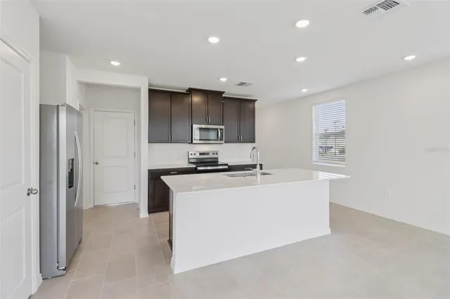 a view of kitchen with stainless steel appliances refrigerator sink and cabinets