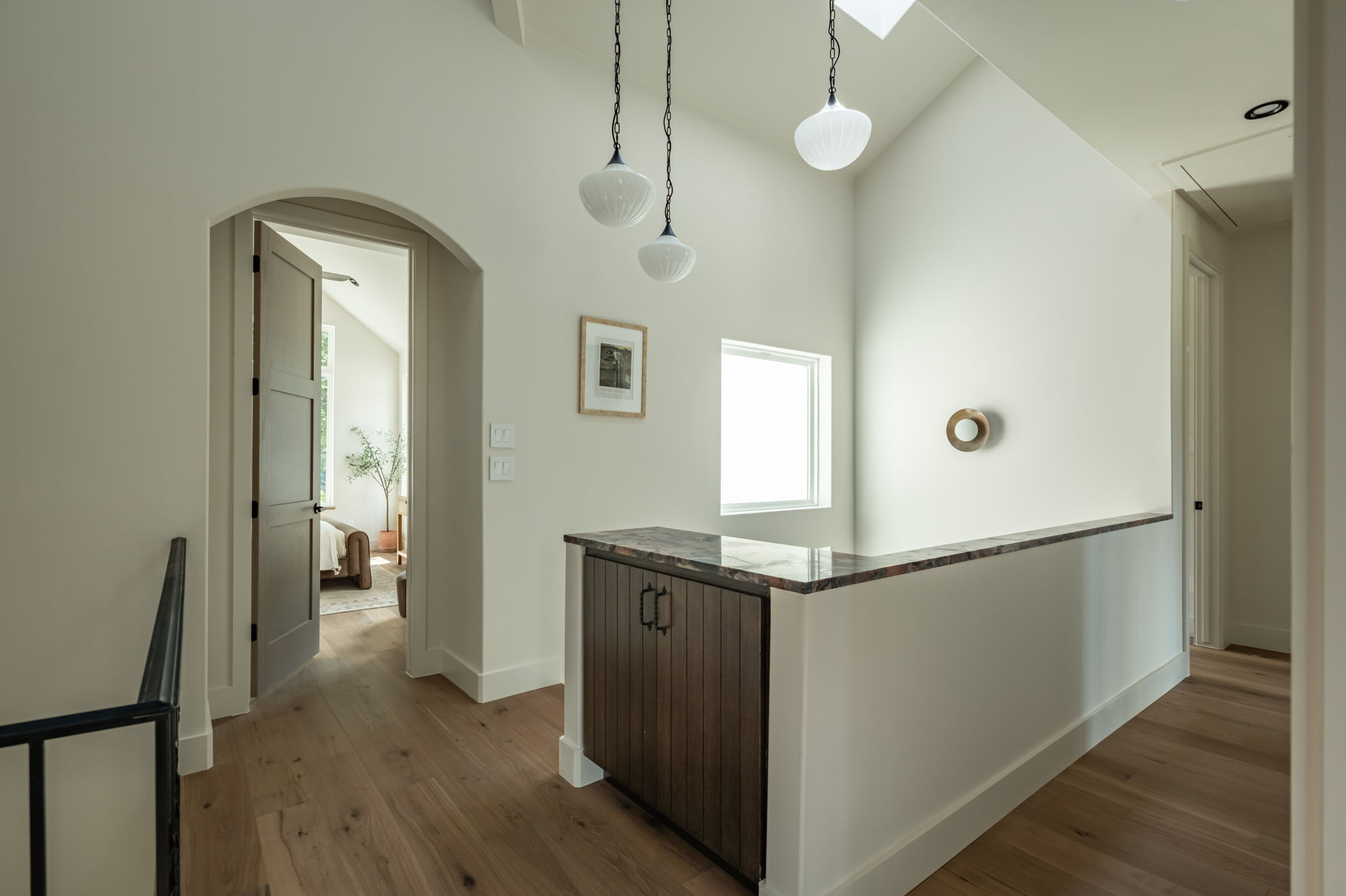 4713 Bolm Road Austin, TX 78702 - Photo 20 of 40 Second-story landing featuring wood-finish flooring, an arched doorway, and a built-in cabinet with a stone countertop