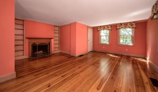 a view of empty room with wooden floor and fireplace