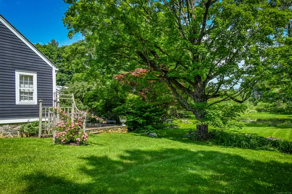 a view of a backyard with table and chairs and large tree