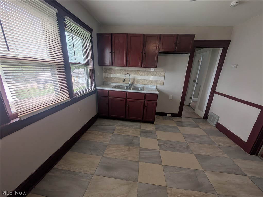 7515 Ottawa Road Cleveland, OH 44105 - Photo 7 of 21 Galley kitchen featuring dark wood cabinetry, a double basin sink, and a tiled backsplash