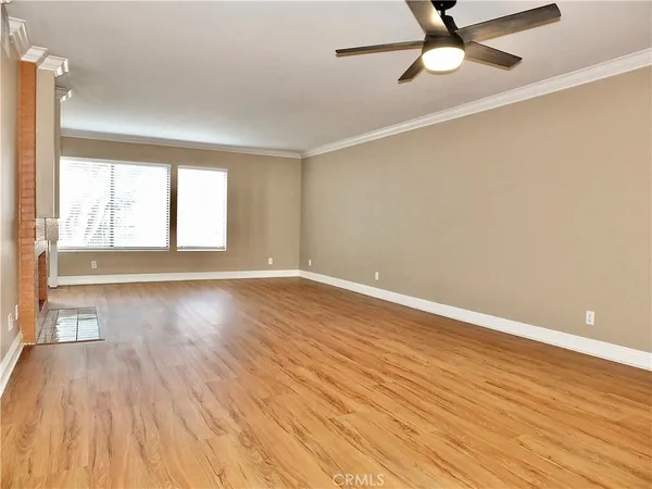 an empty room with wooden floor fan and windows