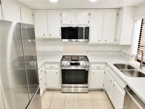 a kitchen with granite countertop a stove a refrigerator and a sink