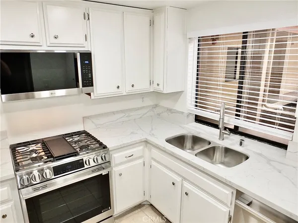 a kitchen with granite countertop a sink stove and cabinets