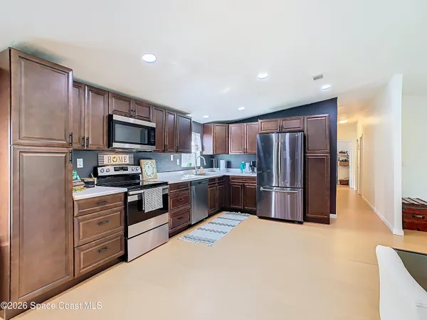 a kitchen with stainless steel appliances a refrigerator a sink a stove top oven a oven with cabinets