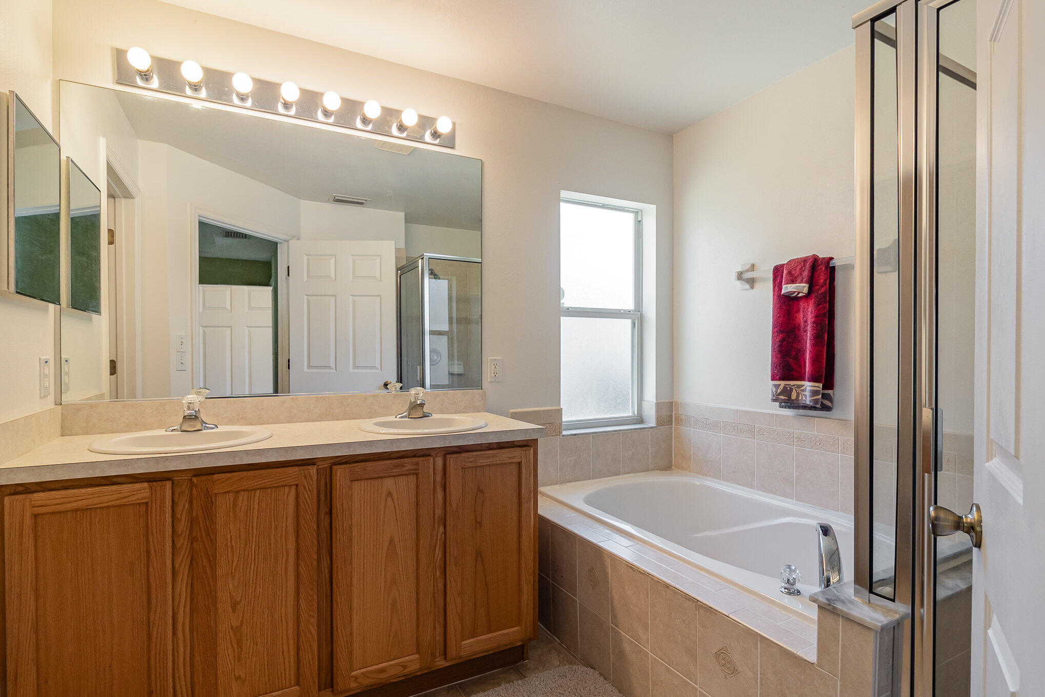 1391 Saxony Road Southwest Palm Bay, FL 32908 - Photo 17 of 28 a bathroom with a tub a double vanity sink and a large mirror