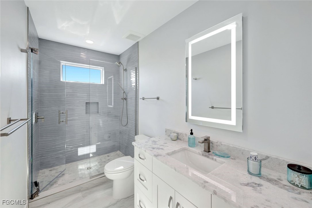 1044 Fish Crow Road Sanibel, FL 33957 - Photo 28 of 36 a bathroom with a granite countertop sink toilet a mirror and shower
