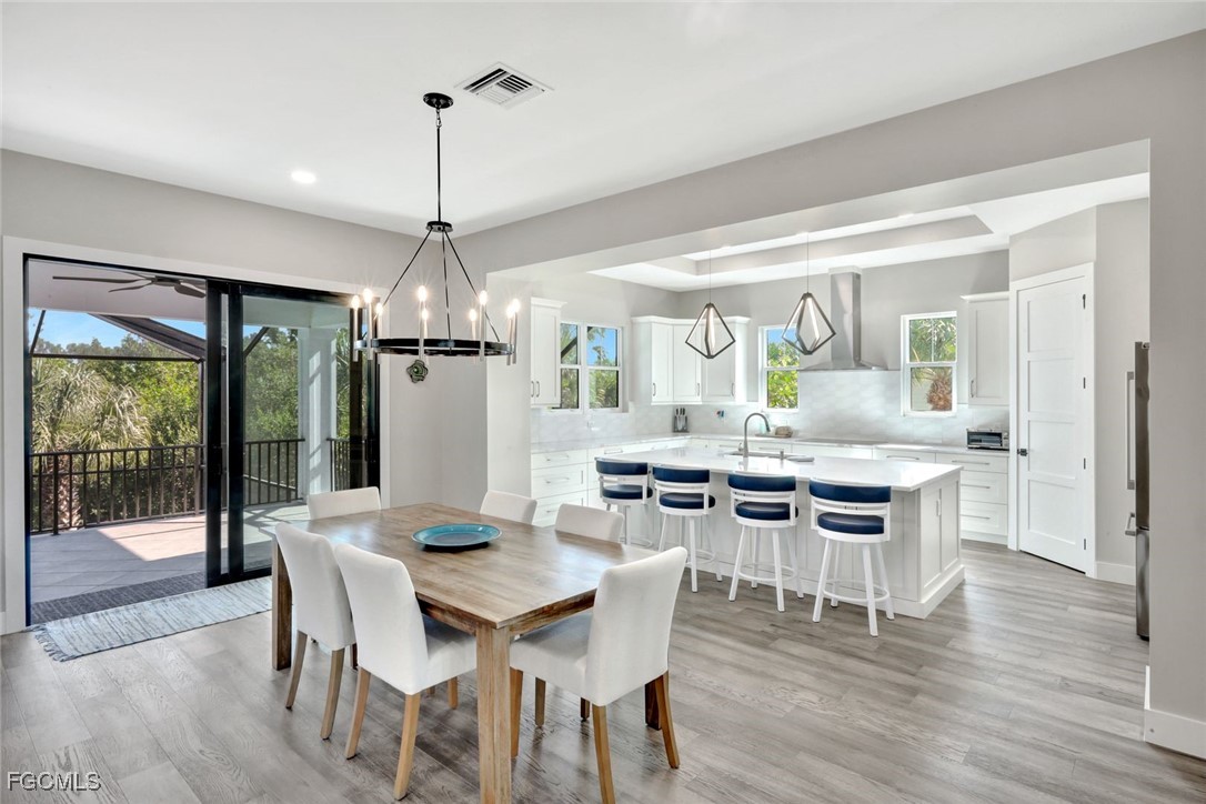 1044 Fish Crow Road Sanibel, FL 33957 - Photo 4 of 36 a dining room with wooden floor a chandelier a wooden table and chairs