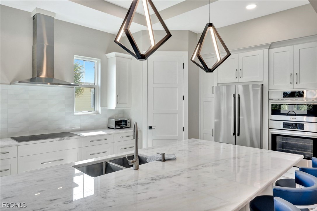 1044 Fish Crow Road Sanibel, FL 33957 - Photo 6 of 36 a kitchen with stainless steel appliances a stove a sink and white cabinets with wooden floor