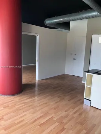 an empty room with wooden floor and mirror