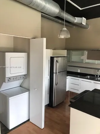 a kitchen with a refrigerator and white cabinets