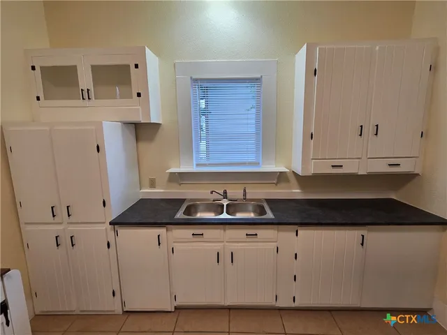 a kitchen with granite countertop white cabinets and sink