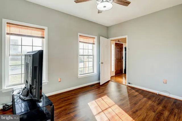 a view of an empty room with window and hardwood floor