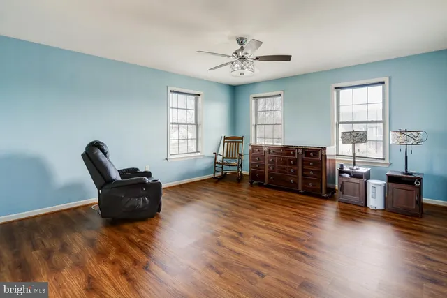a hallway with wooden floor chandelier fan and windows