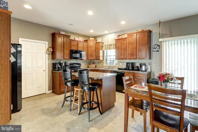 a kitchen with stainless steel appliances kitchen island granite countertop a refrigerator and a stove top oven