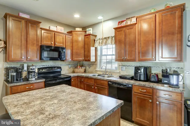 a kitchen with stainless steel appliances granite countertop a stove a sink dishwasher and a microwave oven with large wooden cabinets