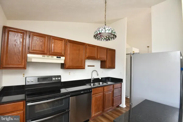 a kitchen with stainless steel appliances granite countertop a sink cabinets and wooden floor