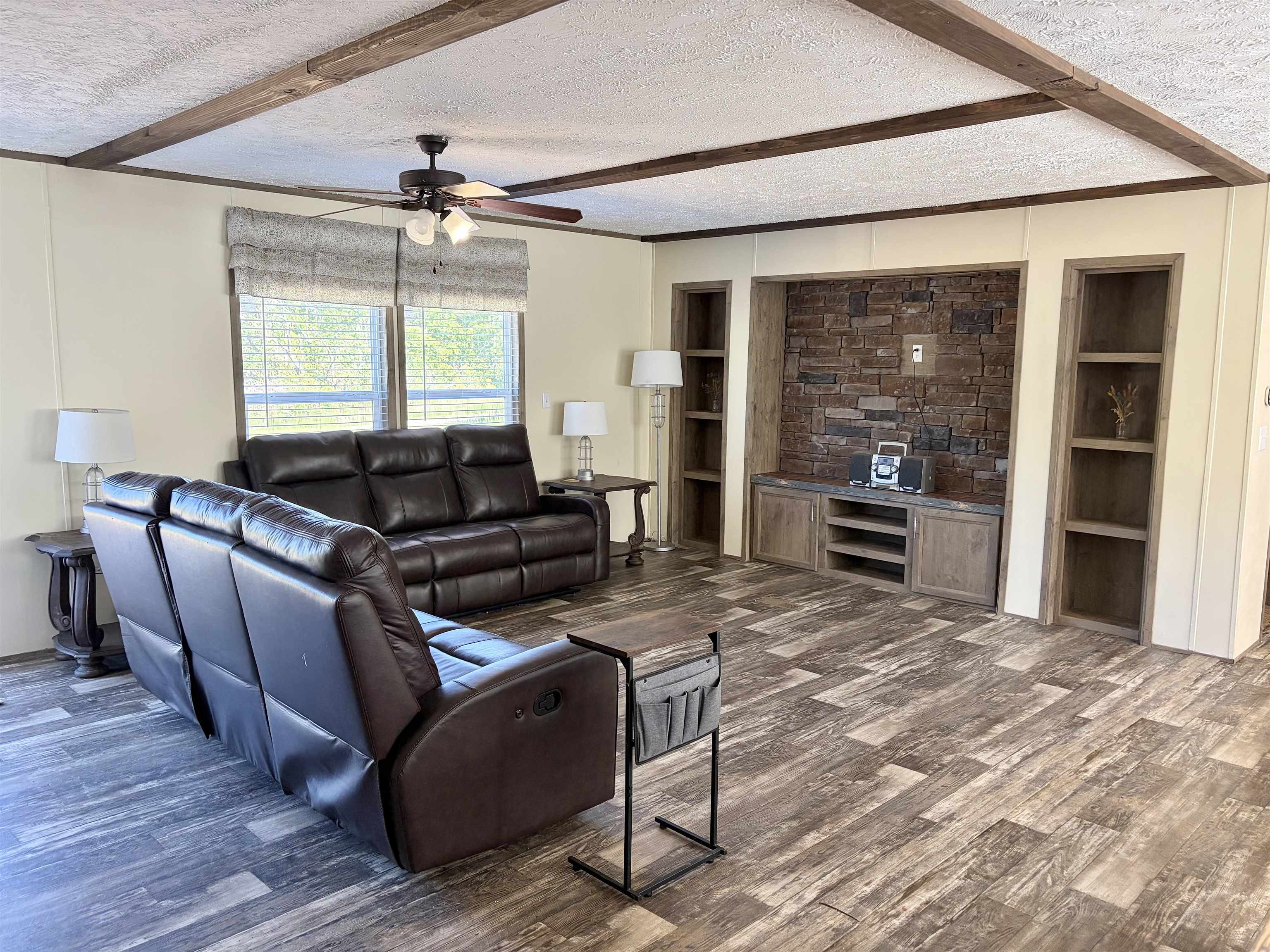2030 Nubbin Ridge Road Middleton, TN 38052 - Photo 4 of 28 Living area featuring wood-finish flooring, exposed ceiling beams, and a built-in entertainment center with stone accent wall