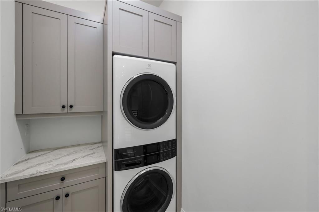16728 Enclave Circle Naples, FL 34110 - Photo 42 of 49 Laundry area with stacked washer and clothes dryer and cabinet space