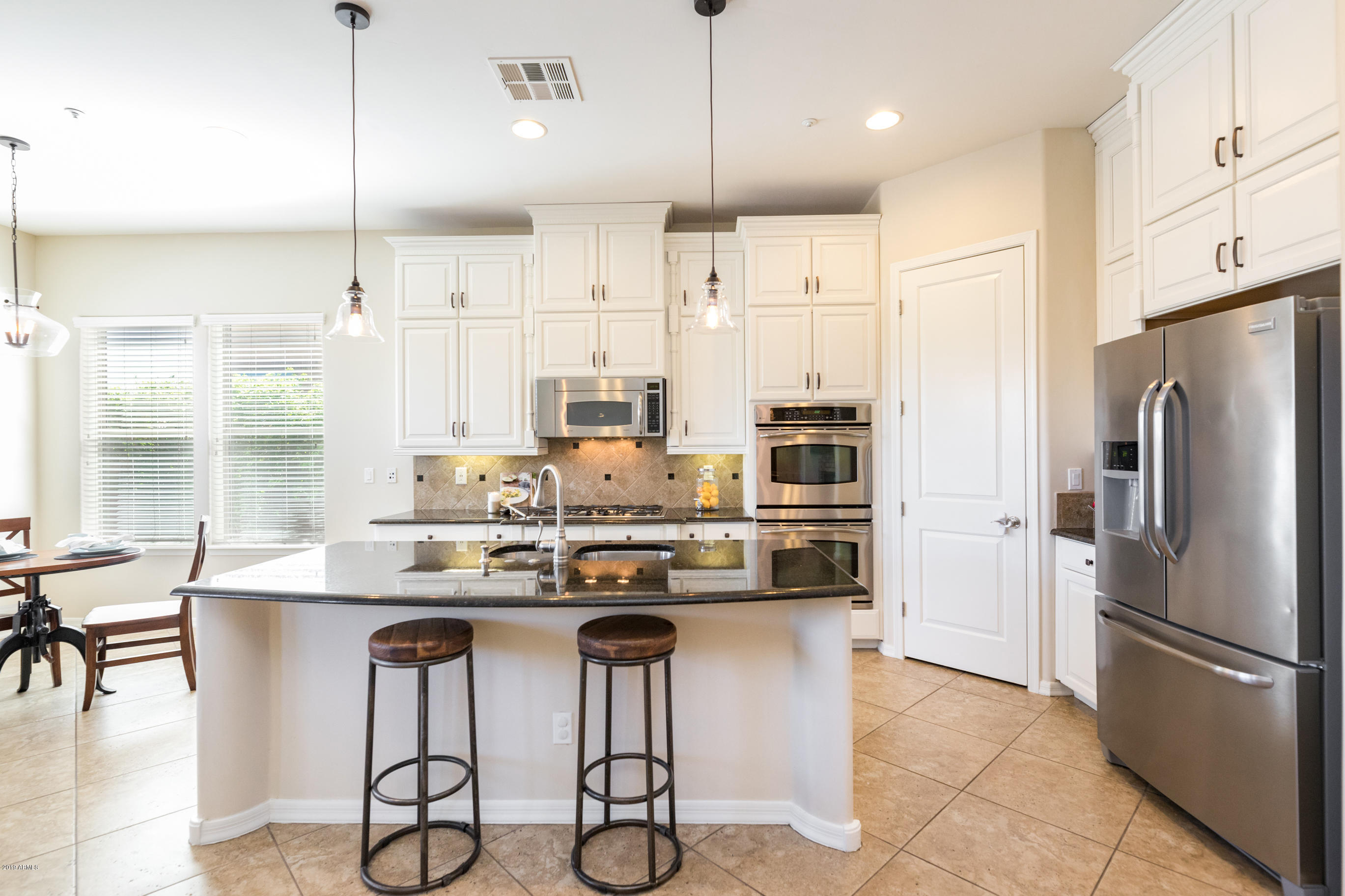 9185 East Canyon View Road Scottsdale, AZ 85255 - Photo 15 of 47 a kitchen with stainless steel appliances kitchen island granite countertop a table chairs and a refrigerator