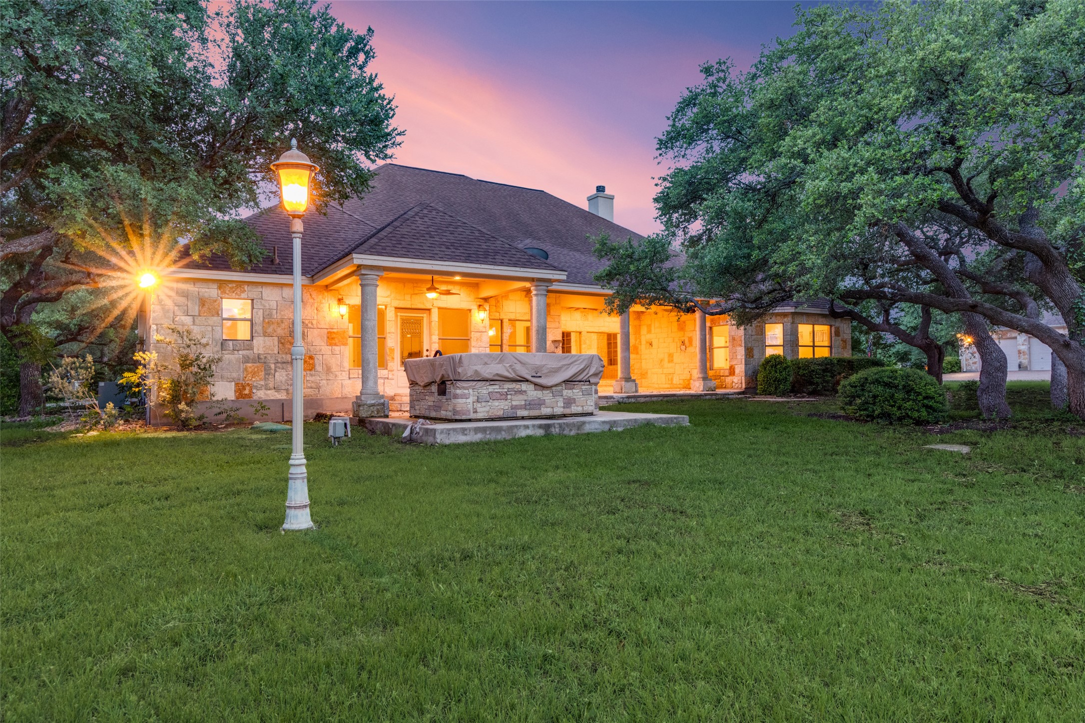 101 Copper Leaf Court Georgetown, TX 78633 - Photo 23 of 31 Expansive lawn with mature trees, stone exterior, covered patio with columns, built-in outdoor feature, and a classic lamppost