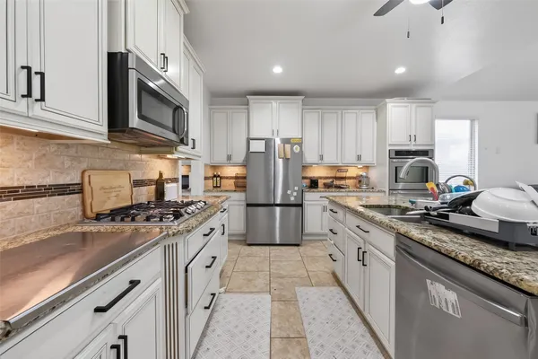 a kitchen with stainless steel appliances granite countertop a stove sink microwave and cabinets