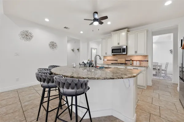 a kitchen with granite countertop a dining table chairs and a refrigerator
