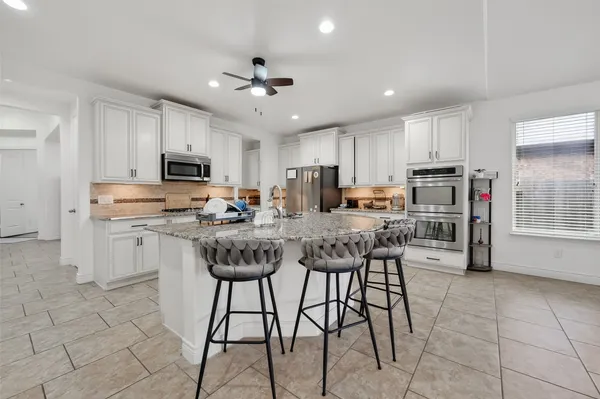 a kitchen with stainless steel appliances granite countertop a stove a sink a microwave a refrigerator and cabinets