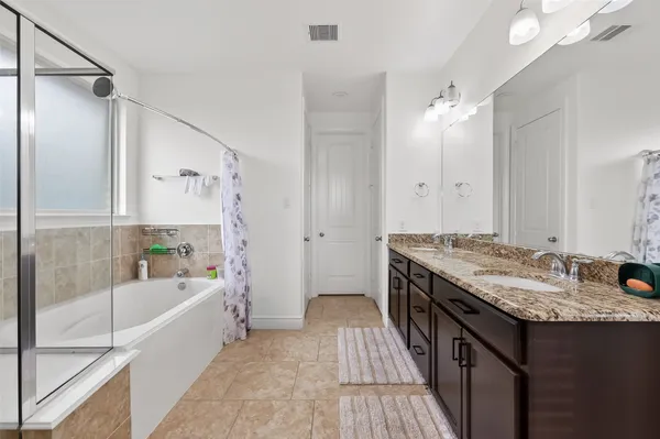 a bathroom with a granite countertop bathtub a sink and a shower