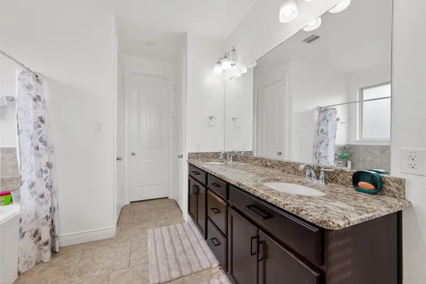 a bathroom with a granite countertop sink a large mirror and a shower