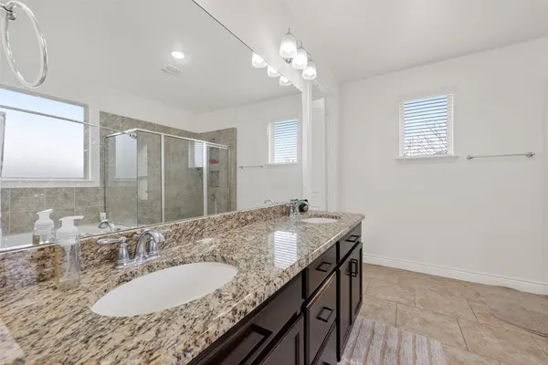a bathroom with a granite countertop sink a mirror and a shower