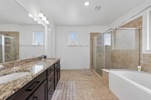 a bathroom with a granite countertop sink a bathtub a mirror and a shower