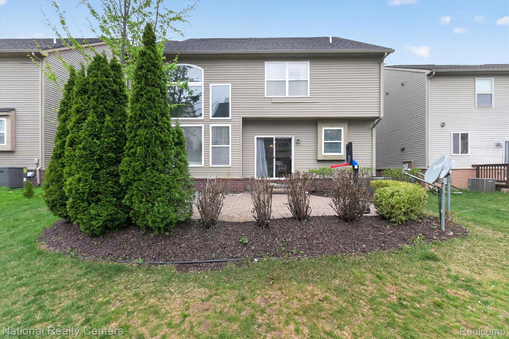 27412 Victoria Road Novi, MI 48374 - Photo 45 of 61 Rear exterior featuring siding, an arched window, a sliding glass door, and a paver patio with landscaping