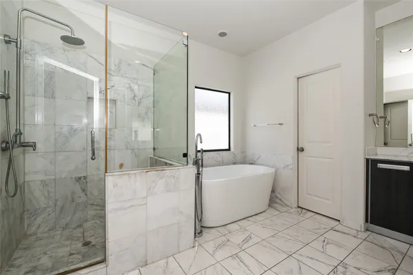 a bathroom with a tub a mirror and shower