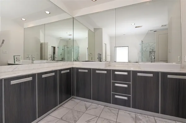 a bathroom with a granite countertop sink a mirror and a refrigerator